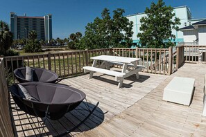 Una terraza de madera con una mesa de picnic y dos sillones de descanso.