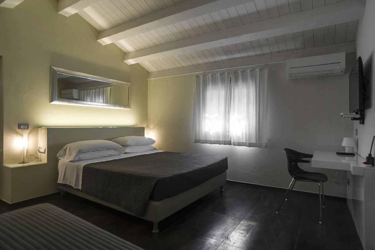 Une chambre à coucher avec un lit, une table de chevet, une chaise et une fenêtre avec des rideaux.