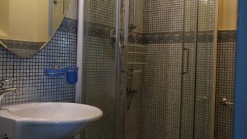 A bathroom with a glass-enclosed shower, a sink, and a mirror.