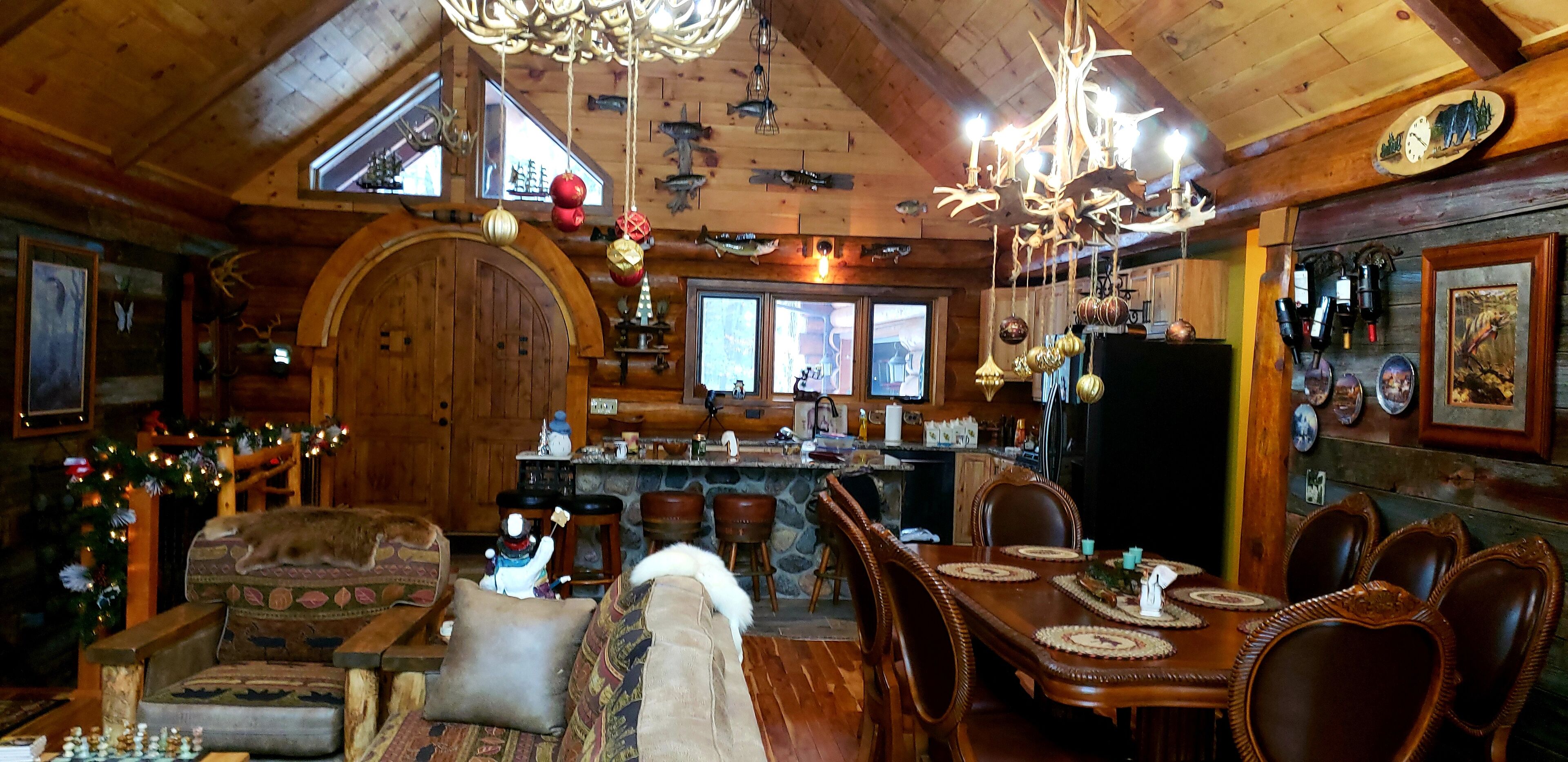 Un acogedor interior de cabaña de troncos con comedor, muebles de madera y chimenea.