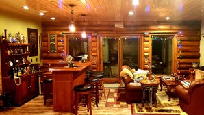 L’intérieur chaleureux d’un chalet en bois comprend un bar, des meubles en cuir et un poisson empaillé accroché au mur.