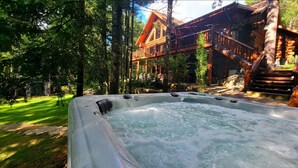 Un bain à remous avec une terrasse en bois et une vue sur un bâtiment au style rustique.