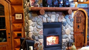 Un intérieur de chalet chaleureux avec une cheminée en pierre, des meubles en bois et une décoration rustique.