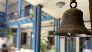 A bell hanging in a room with blue columns and a window overlooking a garden. - Hotel Montecarlo Riobamba (Riobamba)