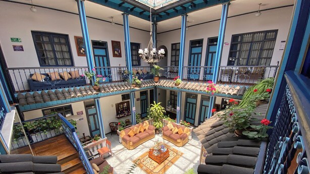 A multi-level atrium with a central seating area, staircases, and balconies with potted plants. - Hotel Montecarlo Riobamba (Riobamba)