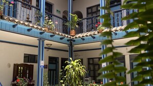 A spacious atrium with a central seating area, multiple balconies with railings, and potted plants. - Hotel Montecarlo Riobamba (Riobamba)