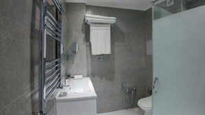 A modern bathroom with a glass shower enclosure, a white sink, and a toilet. - Yurd Hotel (?lisu)