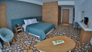 A hotel room with a bed, a desk, a chair, a round table with apples, and a TV. - Yurd Hotel (?lisu)