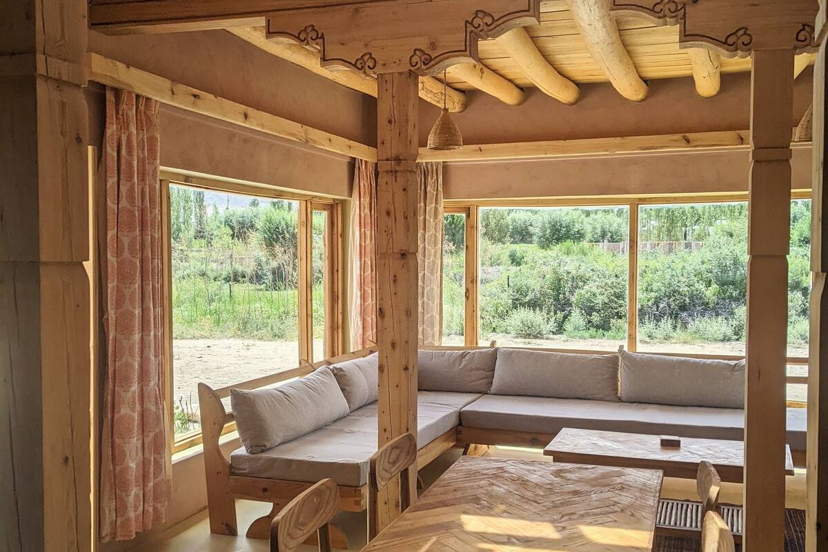 A rustic wooden interior with a large table, benches, and a high ceiling with exposed beams.