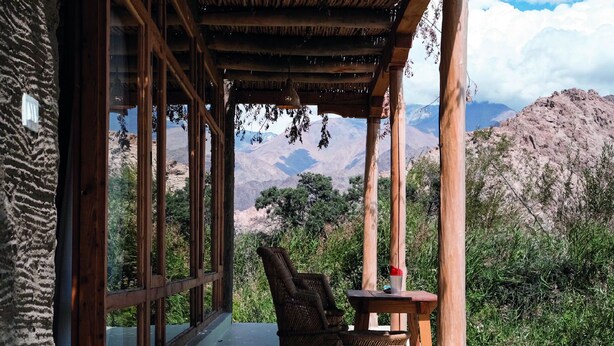 Uma área de estar coberta ao ar livre com vista para montanhas e vegetação.