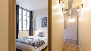 Une chambre d’hôtel moderne avec un lit, une fenêtre et un couloir éclairé.