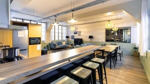 Une cuisine moderne dotée d’un long comptoir, de tabourets de bar et d’un coin repas avec une table et des chaises en bois.