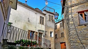 A narrow alley with stone buildings, a metal railing, and potted plants. - Case Vacanze Borgo Faraldi - La Bottega del Fabbro (Villa Faraldi, Liguria)