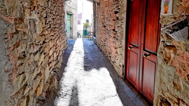 A narrow stone corridor with a wooden door and a number sign. - Case Vacanze Borgo Faraldi - La Bottega del Fabbro (Villa Faraldi, Liguria)