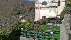 A historic church with a bell tower, a small garden with a table and chairs, and a stone wall. - Case Vacanze Borgo Faraldi - La Bottega del Fabbro (Villa Faraldi, Liguria)