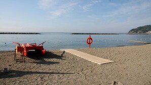 A pebbled beach with a red lifebuoy, a wooden walkway, and a distant pier. - Case Vacanze Borgo Faraldi - La Bottega del Fabbro (Villa Faraldi, Liguria)