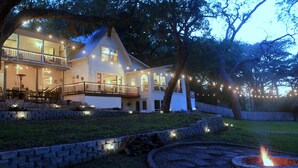 A two-story house with a balcony, stone steps, and a fire pit.