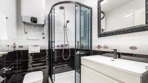 Une salle de bain moderne avec une douche à parois de verre, un lavabo blanc et des toilettes.