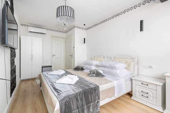 Une chambre à coucher comprenant un lit, des tables de chevet, une armoire, un appareil de climatisation et un téléviseur.