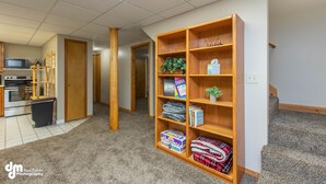 A carpeted hallway with a wooden bookshelf, a kitchen area with appliances, and a door leading to another room. - Eagle's Haven - Lower - 2 bedroom, 1 Bath (Cooper Landing)