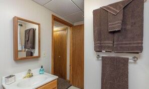 Une salle de bain avec un meuble-lavabo en bois, un évier et un miroir. Des serviettes sont suspendues sur un porte-serviettes.
