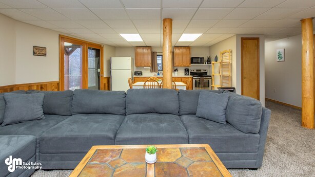 A living room with a sectional sofa, a coffee table with a plant, and a kitchen in the background. - Eagle's Haven - Lower - 2 bedroom, 1 Bath (Cooper Landing)