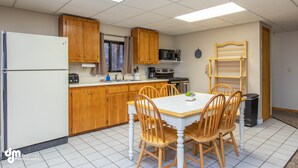 A kitchen with wooden cabinets, a white refrigerator, a microwave, and a dining table with chairs. - Eagle's Haven - Lower - 2 bedroom, 1 Bath (Cooper Landing)