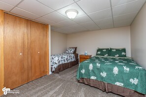 Un dormitorio con dos camas, un armario de madera, una mesita de noche y una lámpara de techo.