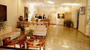 Un hall de hotel con una recepción, sofás y una mesa de centro.