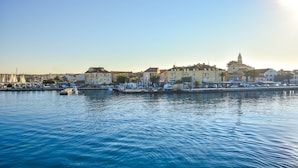 A waterfront cityscape with buildings, a marina, and calm water.