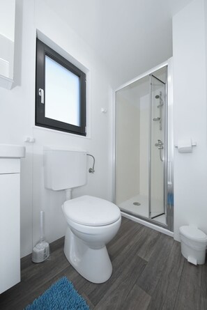 A modern bathroom with a toilet, bidet, and glass-enclosed shower. - Mobile Home Safir (Biograd)