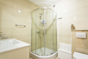 A modern bathroom with a glass-enclosed shower, a white sink, and a toilet.