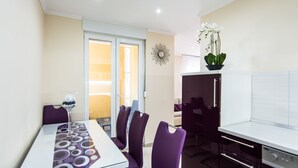 A modern dining area with a glass table, purple chairs, and a decorative glass vase. - Apartment Songbird (Biograd)