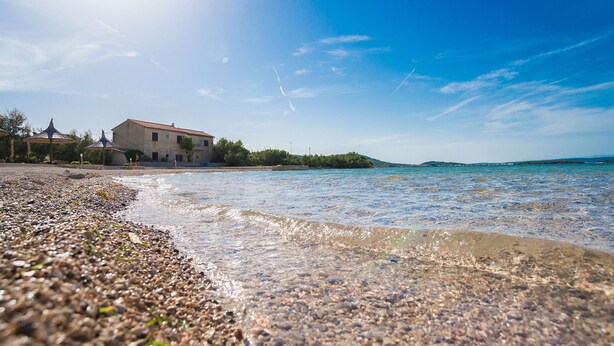 A coastal building with a clear view of the sea and pebbled beach. - Apartments Tarragon (Ugrinic)