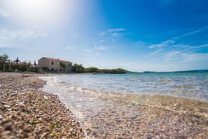 A coastal building with a clear view of the sea and pebbled beach. - Apartments Tarragon (Ugrinic)