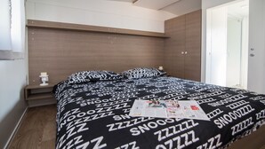 A bedroom with a bed, a nightstand, a window, and a door. - Mobile Home Frangipani 1 (Biograd)