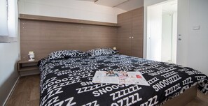A modern bedroom with a bed, a nightstand, and a window.