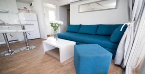 A modern living room with a blue sofa, a white coffee table, and a vase with white flowers.
