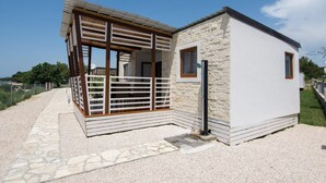 A modern building with a stone facade, a wooden deck, and a metal gate. - Mobile Home Plumeria 1 (Biograd)