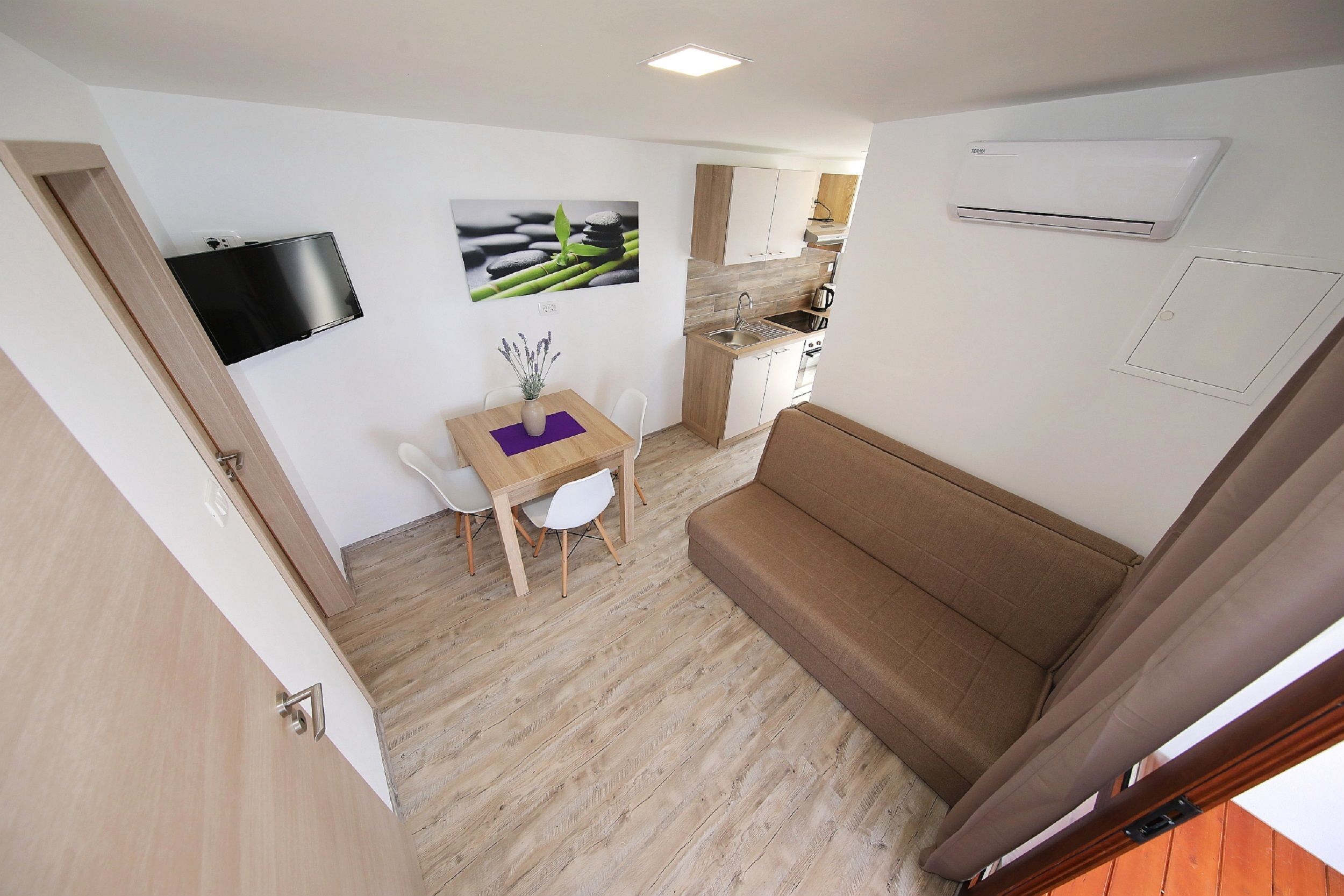 A compact living space with a kitchenette, a dining area, and a sofa.