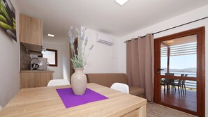 A modern room with a wooden table, a vase with lavender, a sofa, and a view of the outdoors through a glass door. - Mobile Home Plumeria 3 (Biograd)