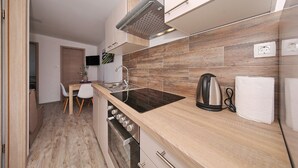 A modern kitchen with wooden flooring, a built-in oven, a sink, and a kettle. - Mobile Home Plumeria 3 (Biograd)