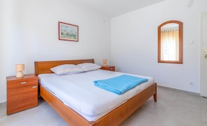 Ein Schlafzimmer mit einem hölzernen Bett, zwei Nachttischen, einem Beistelltisch, einem gerahmten Bild und einem Spiegel.