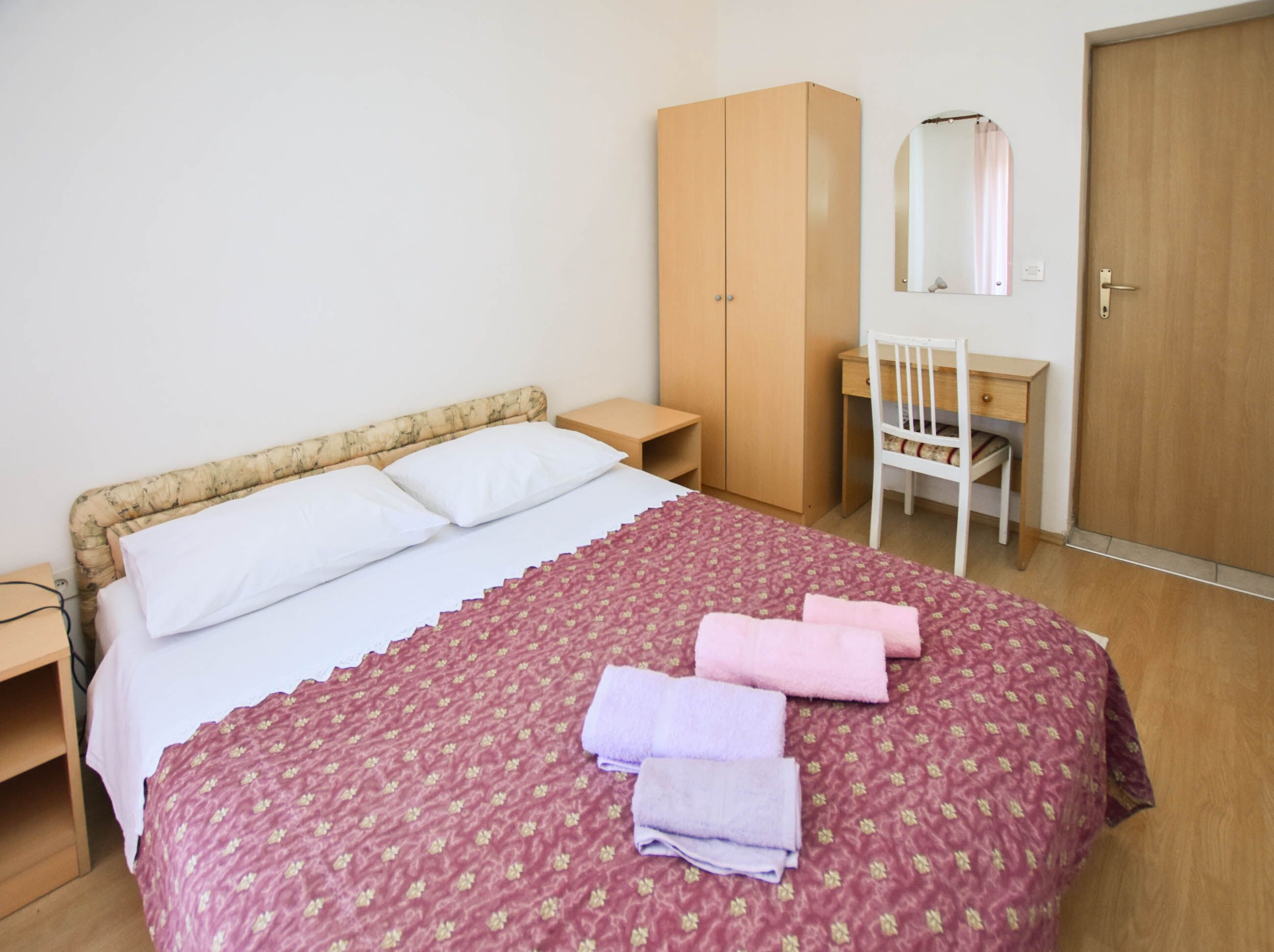 Un dormitorio con cama, armario, escritorio y silla.