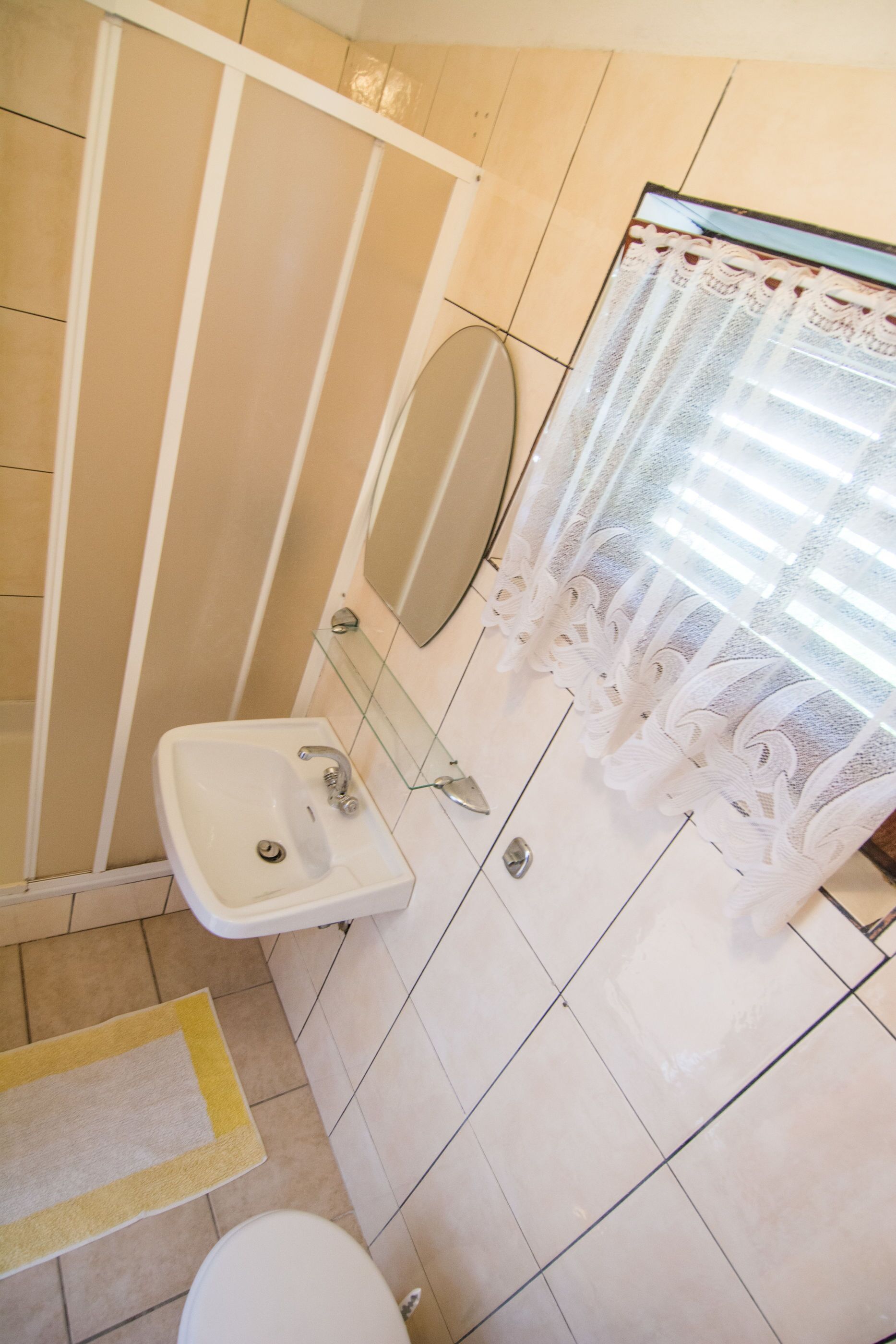 A bathroom with a sink, mirror, and shower.