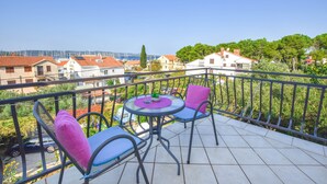 A balcony with two chairs and a table, overlooking a residential area with houses and trees. - Apartments Grapevines (Biograd)
