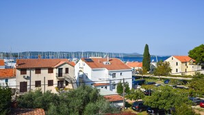 A coastal residential area with houses, a marina, and a clear blue sky. - Apartments Grapevines (Biograd)