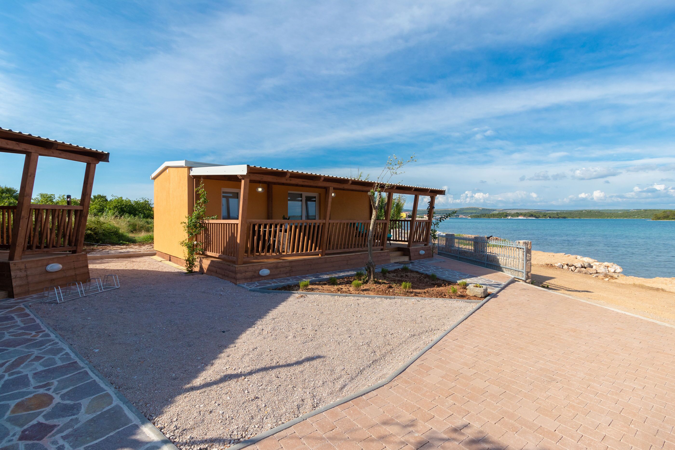 A beachside property with a wooden deck, a covered patio, and a view of the sea.