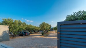 A parking area with gravel, trees, and a gated entrance. - Mobile Home Pecten 01 (Pakostane)