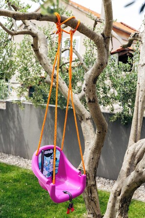 A pink swing hanging from a tree branch. - Apartments Turritella (Biograd na Moru)
